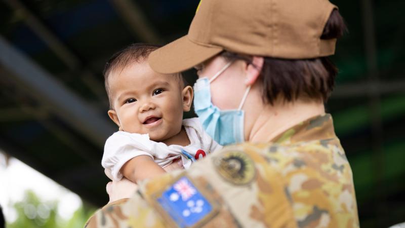 Australian Army officer Captain Sarah Kelly, public affairs officer, holds a child from the local community at Macarascas Elementary School, Palawan, Philippines. Photos: Corporal Brandon Grey
