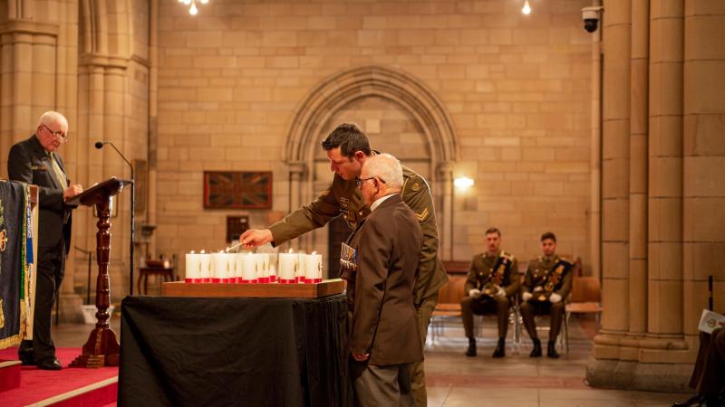 Soldiers of 6RAR and members of the Long Tan Veterans Association light a candle during the Battle of Long Tan service held at St John's Cathedral. Photo: Captain Cody Tsaousis