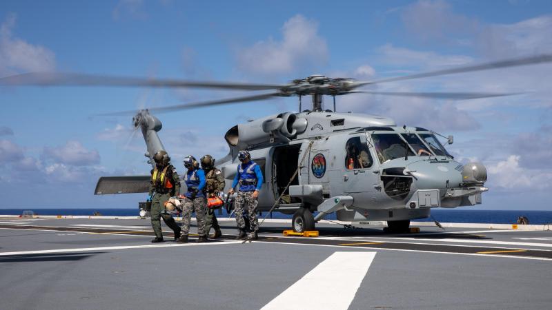 Royal Australian Navy medical officers Commander Robert Turner and Lieutenant Cody Nash transfer a simulated casualty from a MH-60R Seahawk during a training exercise on board HMAS Canberra. Photo: Petty Officer Christopher Szumlanski