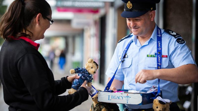 Flight Sergeant Geoff McLaughin, from No. 77 Squadron at RAAF Base Williamtown, sells a Legacy bear to Louise Neider in Newcastle during Legacy Week. Photos: Corporal Melina Young