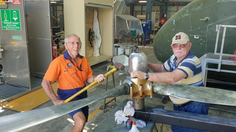 Warrant Officer Kevin ‘Skeet’ Parker, left, removing the dome nut from a propeller in the paint shop at the RAAF Townsville Aviation Heritage Centre. Photo: Flight Sergeant Michael Hartley