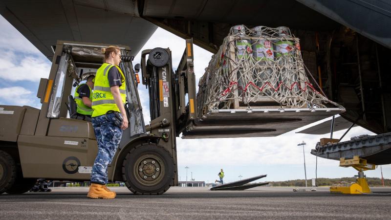 Aviators from No. 22 Squadron load liquefied petroleum gas tanks into a C-130J Hercules aircraft at Port Macquarie, New South Wales. Photo: Leading Aircraftman Chris Tsakisiris