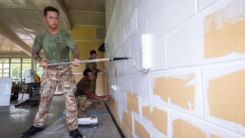 British Army Lance Corporal Shane Bundy, left, PNGDF Lance Corporal Clement Nibabe, kneeling, and Australian Army Sapper Anthony Toigo, paint the guardhouse walls during Exercise Puk Puk at Goldie River Training Depot. Photo: Sergeant Nunu Campos