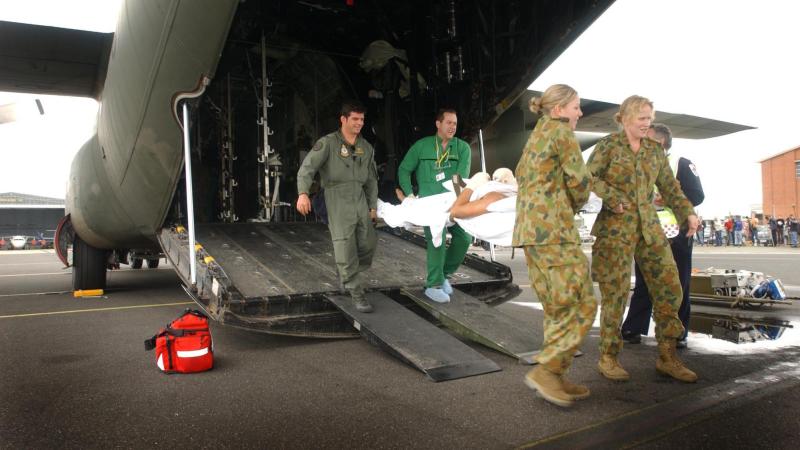 Squadron Leader Steve Cook, back left, a paramedic, Leading Aircraftwoman Hayley Edwards, front left, and Flying Officer (now Wing Commander) Kim Davey carry a Bali bombing victim from a C-130 Hercules. Photo: Sergeant Troy Rodgers