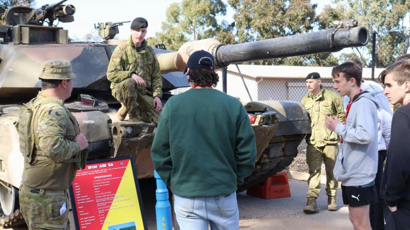 Sergeant Steven Banks, left, and Troopers Nic Spry-Gellert and Oscar Johnson educate students from the Defence Work Experience Program on the M1A1 Abrams main battle tank. Photo: Trooper Marshall Stanfield