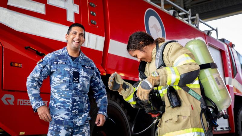 Air Force Indigenous Youth program participant Tallira Hopkins tries on the firefighter uniform with firefighter Leading Aircraftman Ray Solinas at RAAF Base Amberley, Queensland. Photos: Leading Aircraftwoman Kate Czerny