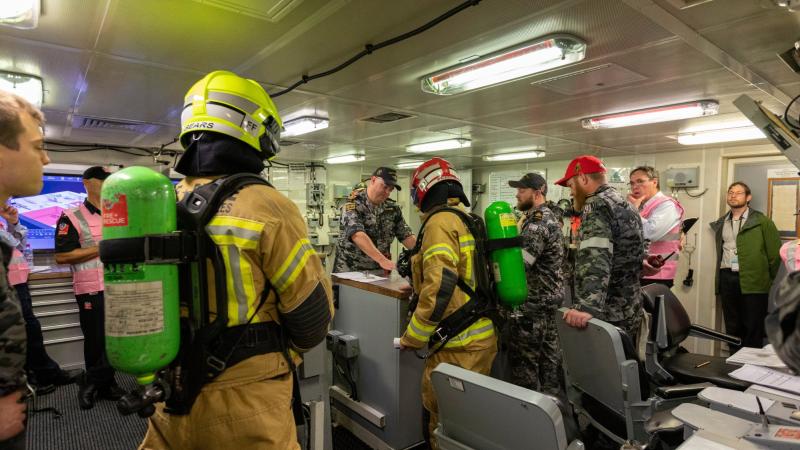 HMAS Brisbane crew, Fire and Rescue NSW and exercise observers gather in the Damage Control Centre on board Brisbane during Exercise Vulcan Phoenix at Fleet Base East, Sydney. Photos: Able Seaman Benjamin Ricketts