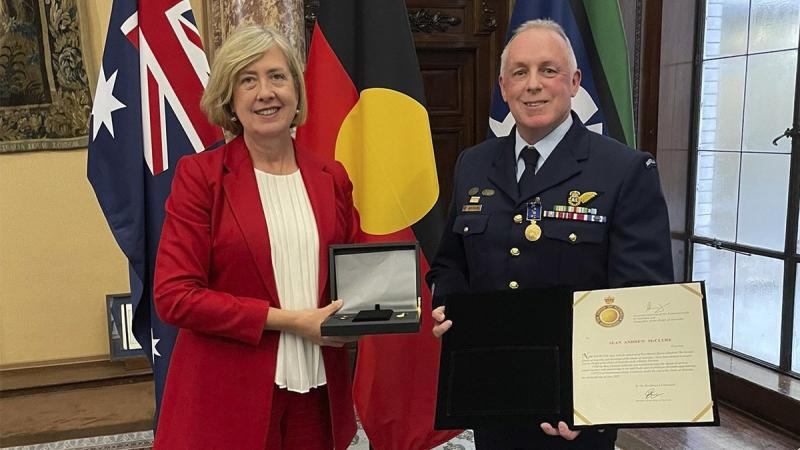 Warrant Officer Sean McClure standing with Australia’s Acting High Commissioner to London, Lynette Wood, with his Medal of the Order of Australia.