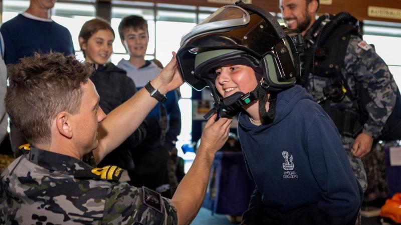 Lieutenant Joel Woods from Clearance Diver Team Four helps Dodhi with a bomb suit helmet during his tour at the Fremantle Ports Maritime Day in Western Australia. Photo: Leading Seaman Ernesto Sanchez
