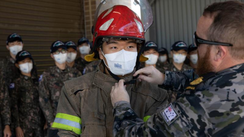 Warrant Officer Tristan Smith, right, assists a midshipman from the Republic of Korea Navy get into a fire suit at the Royal Australian Navy School of Survivability and Ship Safety in Jervis Bay, NSW. Photos: Leading Seaman Ryan Tascas