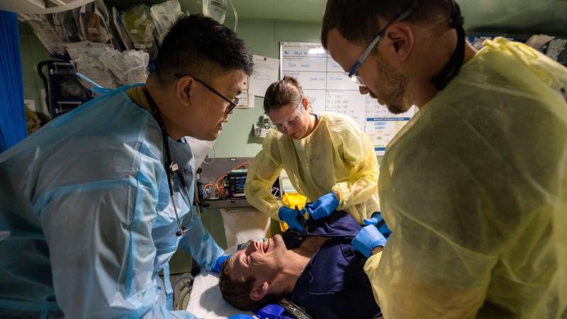 Royal Australian Navy and Royal Malaysian Navy medical officers a conduct a capability demonstration on a volunteer casualty in HMAS Adelaide's resuscitation bay. Photo: Leading Seaman Sittichai Sakonpoonpol