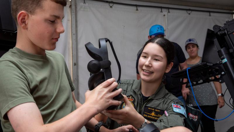 Pilot Officer Maylee Neary hands over the virtual reality headset to Lachlan at the Wings Over Illawarra Air Show. Photo: Leading Aircraftman Chris Tsakisiris