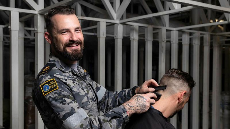 Chief Petty Officer Jessie McFarland runs a barbershop for charity on board HMAS Adelaide. Photo: Leading Seaman Sittichai Sakonpoonpol