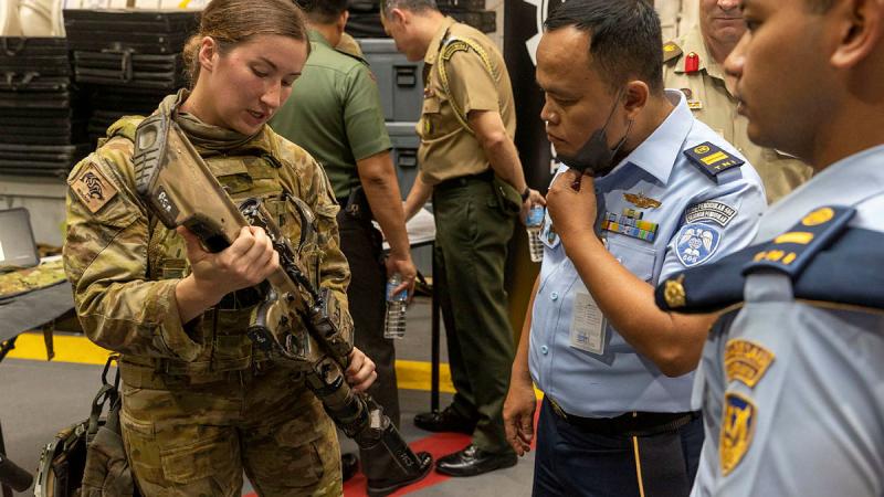 Australian Army signaller Christie Dutra shows members from the Indonesian National Armed Forces the Austeyr Enhanced F88 at HMAS Adelaide’s Defence Industry Expo. Photo: Leading Seaman Nadav Harel