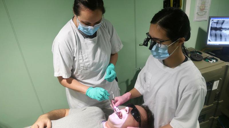 Leading Seaman Stacey Allen, left, and Lieutenant Danica Zhan provide dental care to Leading Seaman Damien Ripley while embarked in HMAS Stalwart.