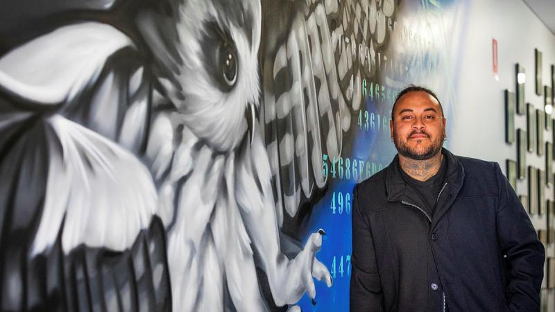  Artist and Ngarrindjeri man Thomas Readett stands beside his artwork displayed at 462 Squadron Headquarters. Photo: Leading Aircraftman Sam Price