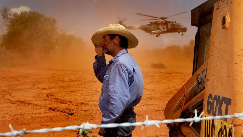 Jack Andrews, Station Manager at Yeeda Station, shelters from the dust as an Australian Army MRH-90 Taipan delivers animal feed. Photos: Leading Aircraftwoman Kate Czerny