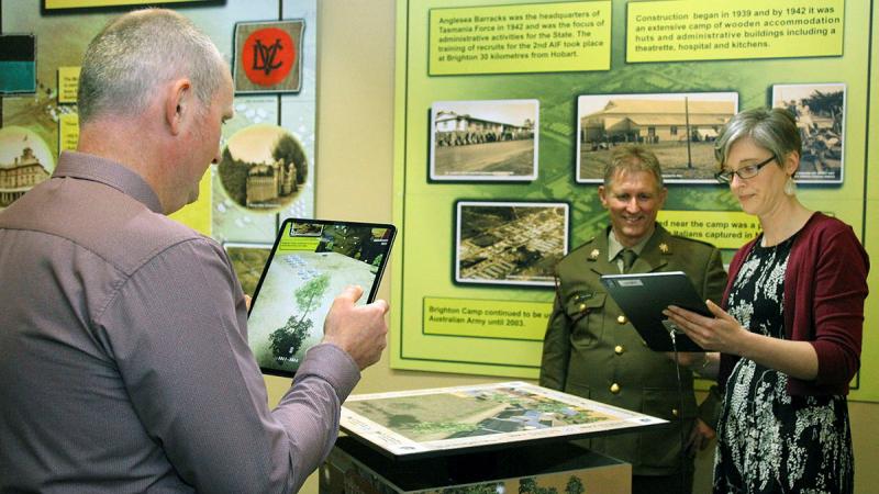 Ben and Kate Hibbert, assisted by Warrant Officer Class 2 Craig Jeffery, view the Windows to the Past Anglesea Barracks Augmented Reality application. Photo: Sergeant W. Guthrie