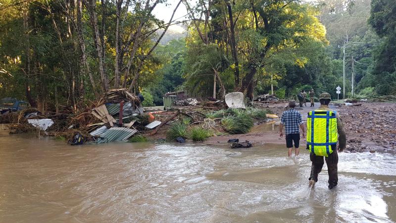 Soldiers and locals wade through flood waters checking properties for stranded residents.