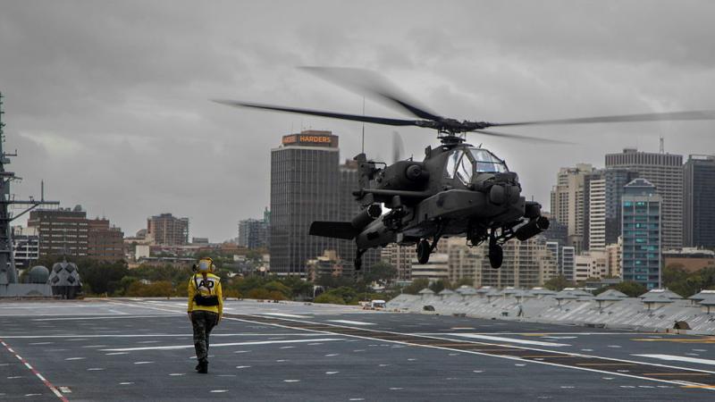 Leading Seaman Avation Support Alyssa Clark marshalls a US Army AH-64E Apache on the deck of HMAS Canberra while the ship is alongside at Fleet Base East in Sydney. Photos: Petty Officer Helen Frank