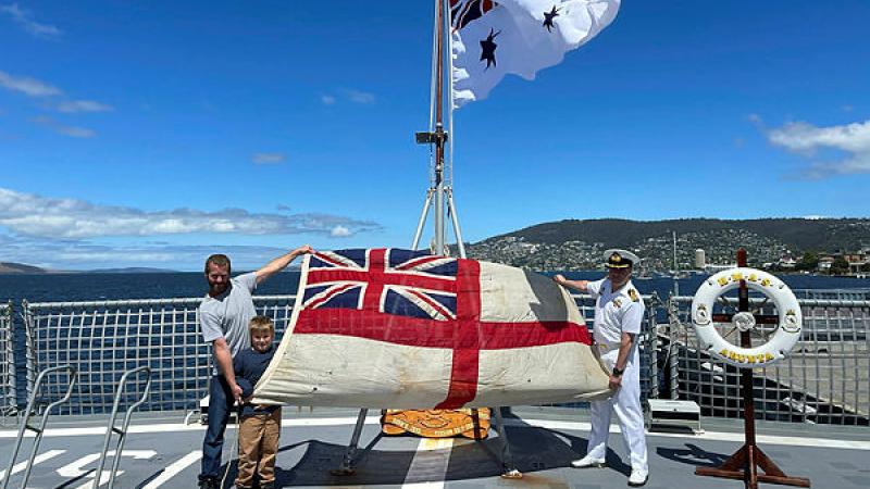 Duncan and Hudson Mennitz present the ensign from HMAS Arunta I to Commanding Officer HMAS Arunta II Commander Jason McBain. Photo: Sub-Lieutenant Tahlia Merigan