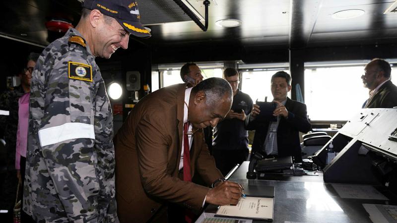 Prime Minister of the Republic of Vanuatu, The Honourable Alatoi Ishmael Kalsakau Ma’aukora, centre, signs the welcome book during a tour of HMAS Canberra. Photo: Leading Seaman Daniel Goodman