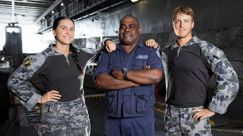 From left, Leading Seaman Sevanna Tansey, Vanuatu Police Maritime Senior Inspector and Executive Officer Gary Aru and Able Seaman Sean Davies stand by the well deck of HMAS Canberra during Operation Vanuatu Assist. Photo: Leading Seaman Matthew Lyall