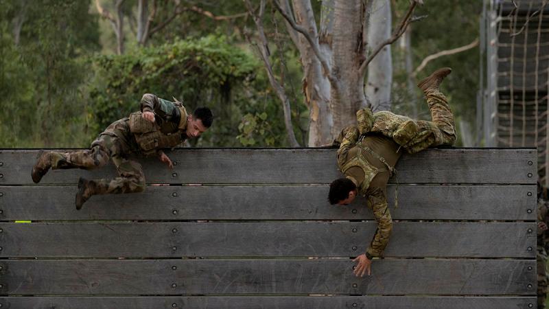 An Australian Army soldier and French Army soldier scale the six-foot wall during a military skills competition as a part of Mission Jeanne d'Arc held at Lavarack Barracks. Photos: Lance Corporal Riley Blennerhassett