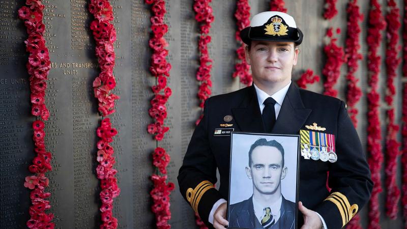  Lieutenant Commander Ashleigh Payne holds a picture of her great-uncle Leading Aircraftman James Geoffrey Payne in front of the Roll of Honour at the Australian War Memorial. Photo: Corporal Michael Rogers
