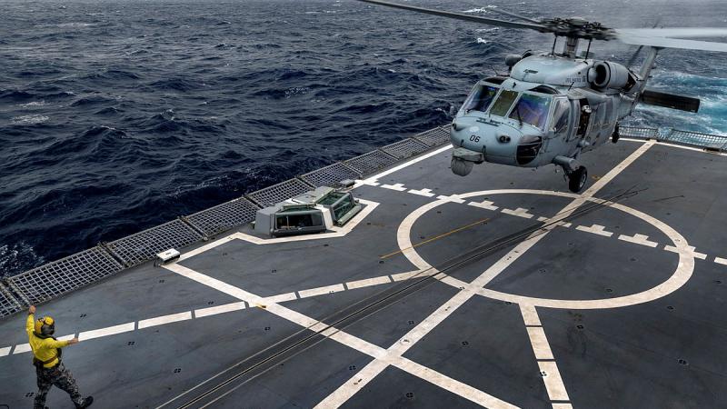 USS America's MH-60S helicopter is marshalled by HMAS Anzac’s Leading Seaman Joshua Leach during deck landing training on board Anzac. Photos: Leading Seaman Jarryd Capper