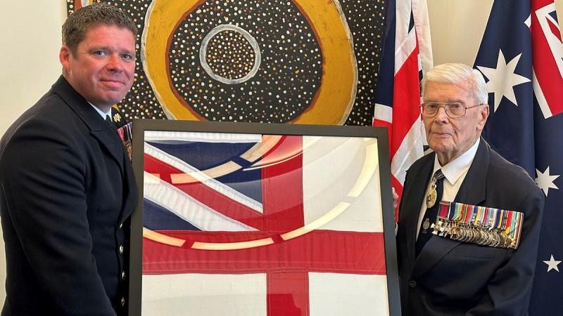 Rear Admiral (retd) Guy Griffiths presents the Royal Navy ensign to Commanding Officer HMS Prince of Wales Captain Richard Hewitt. 