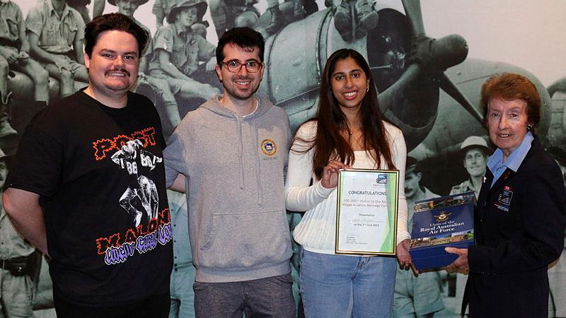 Wagga Aviation Heritage Centre volunteer Christine Wyatt presents Erika Mendes with a certificate and book set, while Kieren Johnston and Haig Vartoukian look on. Photo: Peter Wyatt