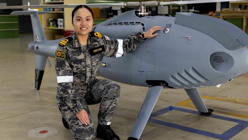 Lieutenant Fiona Nguyen in front of a Shiebel S-100 air vehicle at 822X Squadron, HMAS Albatross. Photo: Petty Officer Justin Brown