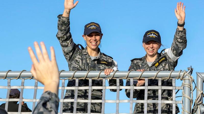 Able Seaman Emma Christ, left, and Leading Seaman Claudia Hardie wave to friends on the wharf as HMAS Toowoomba returns to Fleet Base West in Rockingham, Western Australia. Photo: Chief Petty Officer Yuri Ramsey