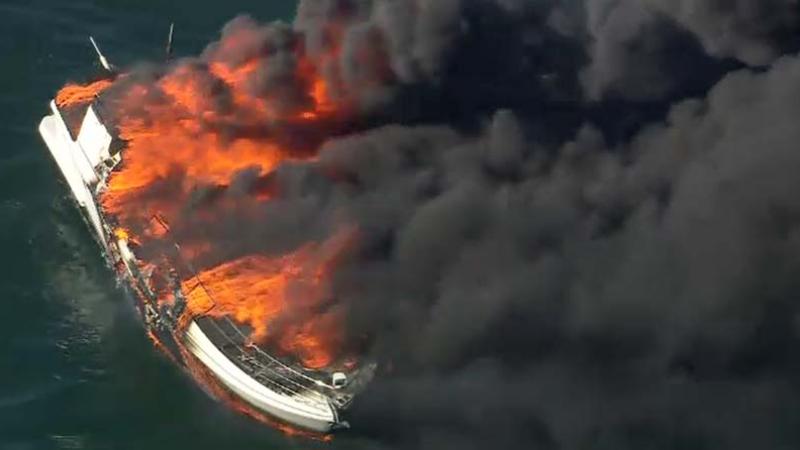 The stricken vessel burns to the waterline after being abandoned.