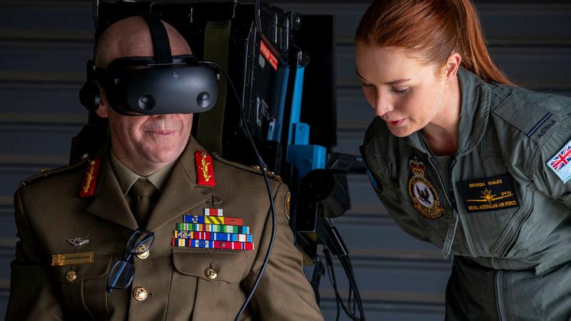 Pilot Officer Georgia Wales leads Head of People Capability, Major General Wade Stothart through the Air Force virtual reality flight simulator during the Defence and Questacon partnership announcement. Photos: Leading Aircraftwoman Annika Smit