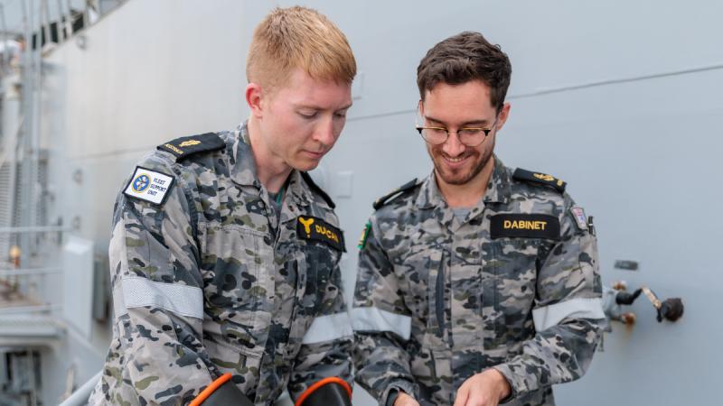 Navy personnel work on a capstan control panel on HMAS Anzac