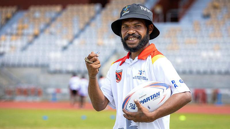 Derrick Akes holds a rugby union ball and whistle during training. 