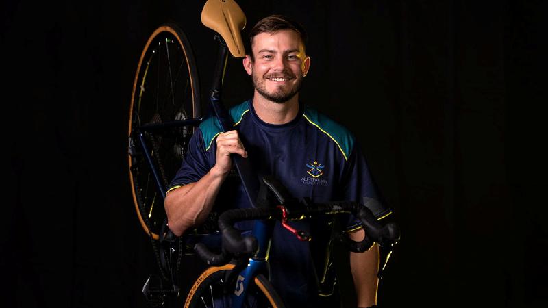  Able Seaman Jamie McGlinchey holding a bike while posing. 