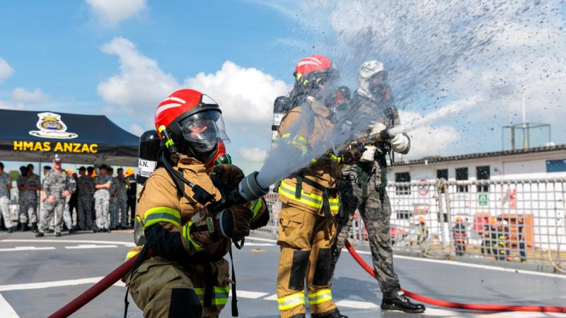 HMAS Anzac sailors spray water during a damage control display for Singapore Navy personnel on board during a regional presence deployment.