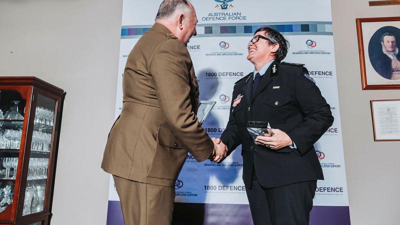 Two people shaking hands while holding their awards