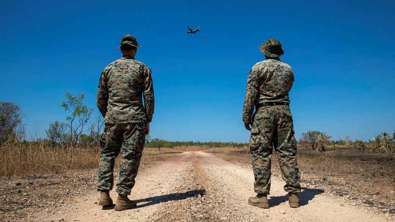 From left, US Marine Corps 1st Lieutenant Kevin Arbeznik and Gunnery Sergeant Emmanuel Alvarado observe an airdrop from a RAAF C-27J Spartan at the Mount Bundy Training Area, Northern Territory. 