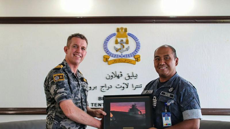 Commanding Officer Commander Cam Hooper, left, presents a photo of NUSHIP Arafura to Captain Haji Mohamad Sarif Pudin bin Matserudin, Acting Commander Royal Brunei Navy. 