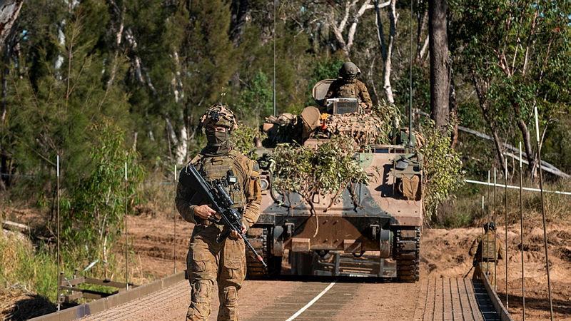 An Australian sapper from the 2nd Combat Engineer Regiment guides an M113 armoured personnel carrier over the new dry support bridge.