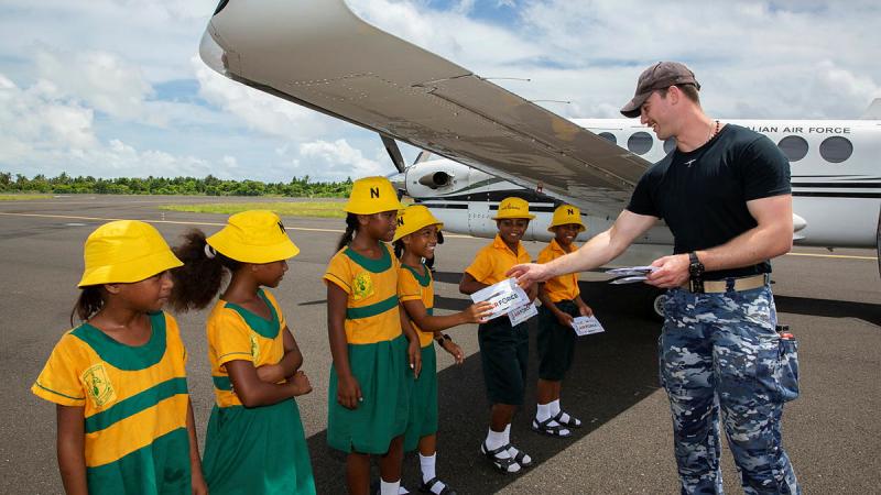 Flying Officer Michael Sullivan presents RAAF mementos to year five children from Bareaumai Primary School in the Republic of Kiribati who visited the RAAF KA350 King Air at Bonriki International Airport during Operation Solania – Island Chief.