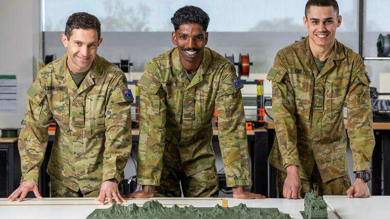 Three soldiers display a 3D model.