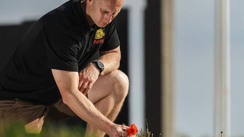 Corporal Justin Wells picks a poppy on the Western Front.