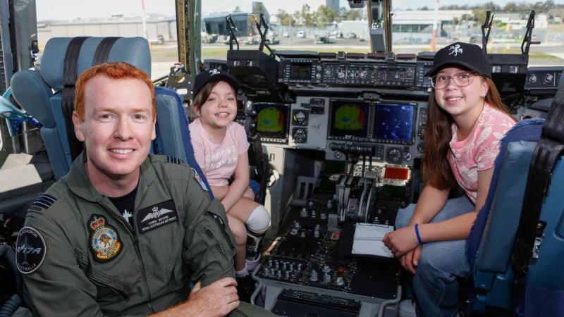 Squadron Leader Chris Moore (left) from 36 Squadron, with patients Jamie (center) and Sophia from the Queensland Children's Hospital, on the flight deck of a C-17A Globemaster III at RAAF Base Amberley.
