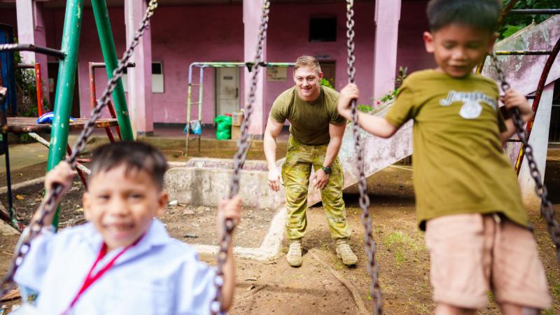 An Australian Army solider pushes children on a swing from Asociacion de Damas de Filipinas Settlement Home Orphanage in Manila, Philippines.