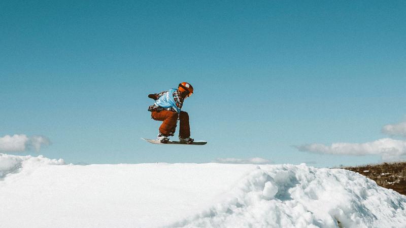 Lieutenant Commander Harriet Cameron jumps over a hill on a snowboard.